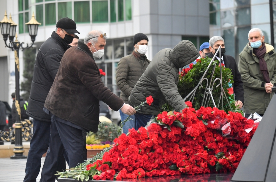 Люди несут портреты к памятнику жертвам Ходжалы «Ана Харайи» в Баку