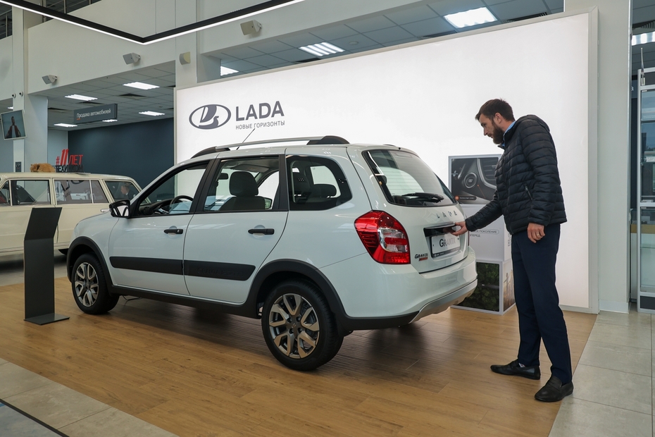 Мужчина осматривает автомобиль  Lada Granta в автосалоне дилерского центра Lada