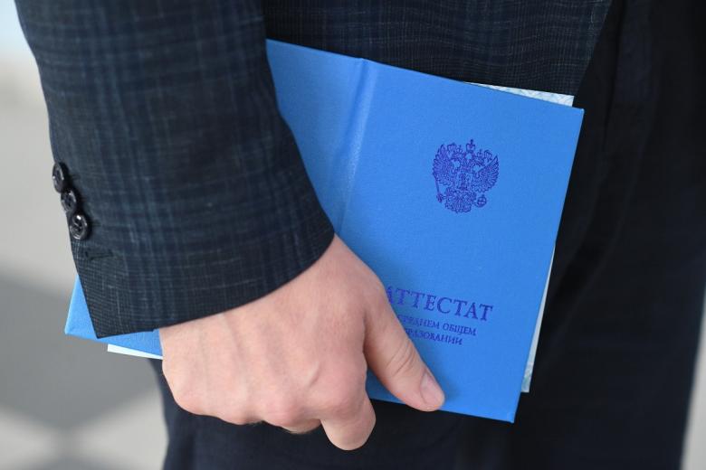 Выпускник держит аттестат о среднем общем образовании