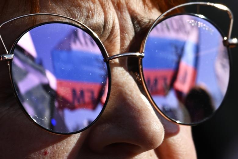 Женщина смотрит трансляцию митинга-концерта, посвященного воссоединению Крыма с Россией, у Большой спортивной арены «Лужники» в Москве