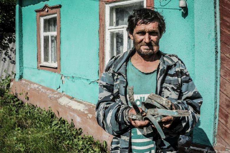 Житель Козинки показывает осколки, найденные в огороде