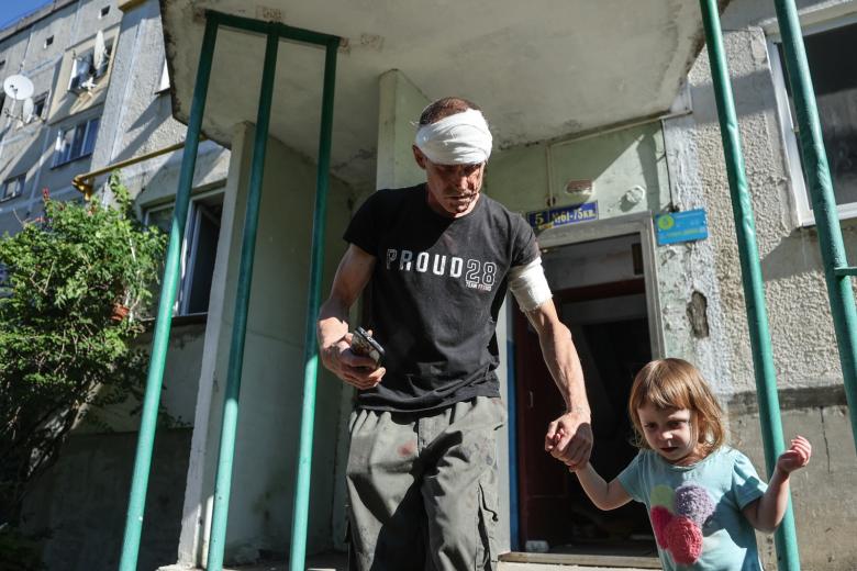 Мужчина, пострадавший в результате обстрела ВСУ, и ребенок на одной из улиц города. Новая Каховка