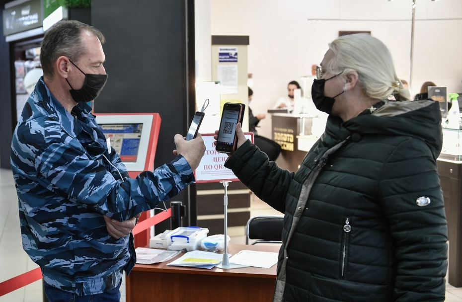 Женщина в защитной маске предъявляет QR-код на входе в торговый центр в Симферополе