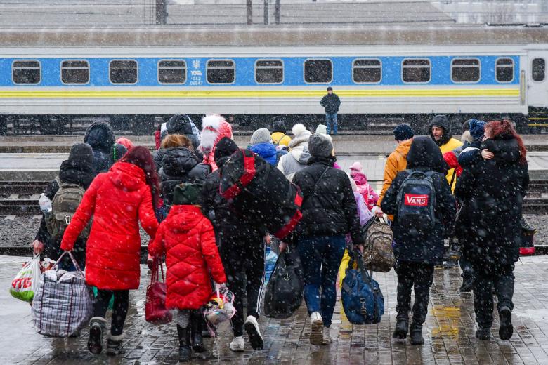 Люди ждут поезда на железнодорожном вокзале, чтобы эвакуироваться в Россию