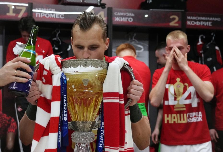 Игроки  «Спартака» в раздевалке празднуют победу в Кубке России по футболу сезона 2021/2022. На первом плане: вратарь Александр Максименко пьет шампанское из кубк