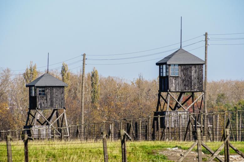 Забор и сторожевые башни, окружающие жилые здания в концентрационном лагере Освенцим-Биркенау