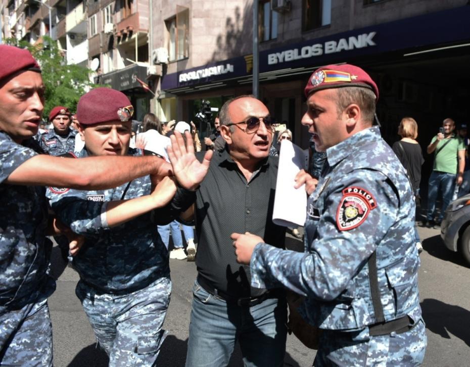 Сотрудники полиции и участник протеста на фоне эскалации в Нагорном Карабахе на площади Республики в Ереване