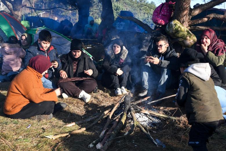 Беженцы у костра в лагере нелегальных мигрантов на белорусско-польской границе