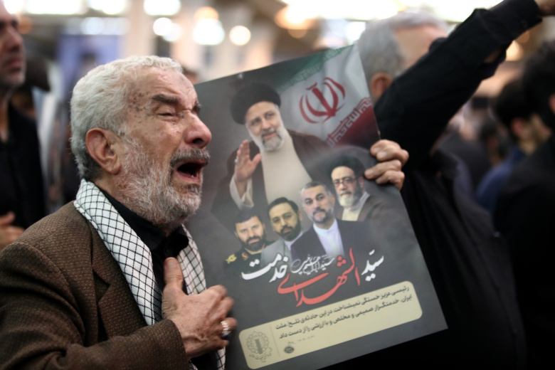 Скорбящий держит плакат покойного президента Ирана Ибрахима Раиси во время церемонии похорон у храма Имама