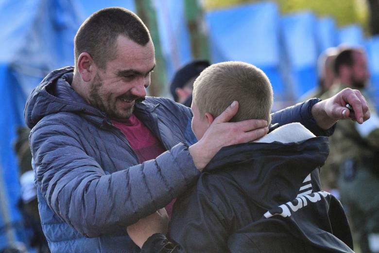 Мальчик Матвей обнимает своего отца Максима после двухмесячной разлуки в специальном пункте по оказанию помощи эвакуированному населению в селе Безыменное