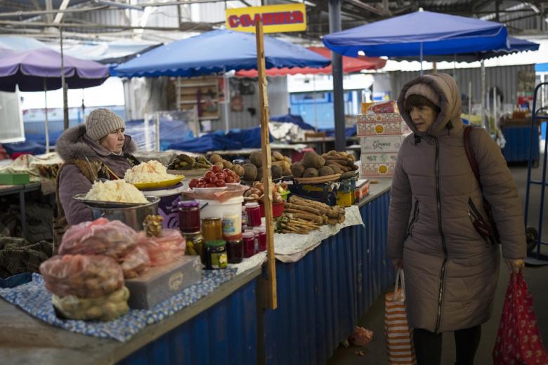 Женщина проходит мимо продавца на рынке в Киеве