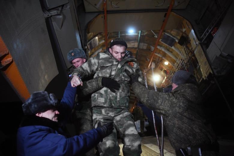 Сотрудники военной полиции помогают раненому освобождённому из плена российскому военнослужащему спуститься с самолета на аэродроме Чкаловский
